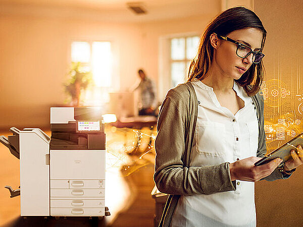 Eine Frau hat ein Tablett in der Hand und dahinter steht ein Drucker.
